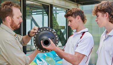 Two high school students with Melbourne Zoo educator investigating an object. 