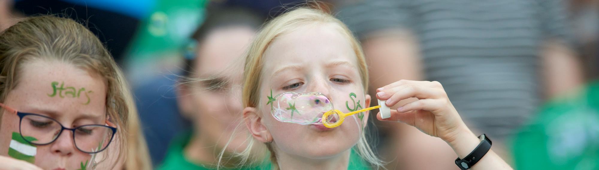 Young girl wearing face paint blowing bubbles for the Bubble World Record Attempt.