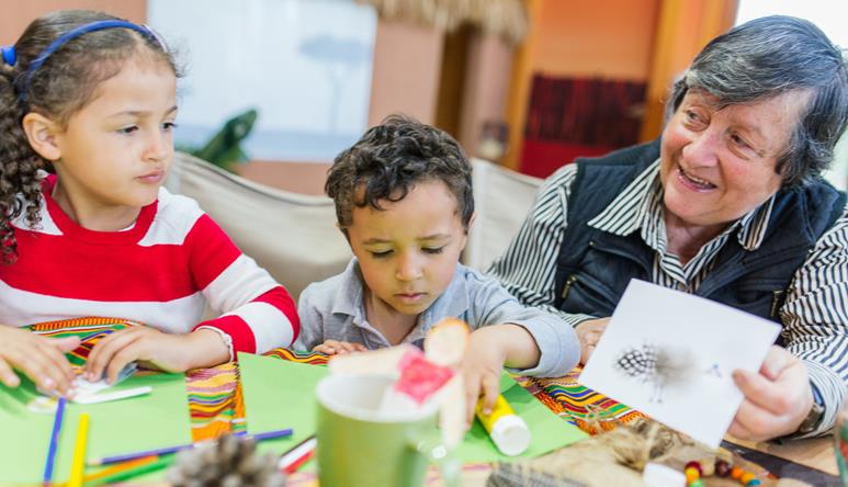 Two young guests making craft with paper and markers, joined by an elder guest to the right.