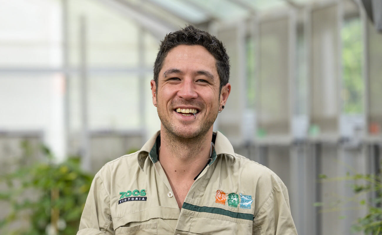 A male zoo keeper smiling at the camera