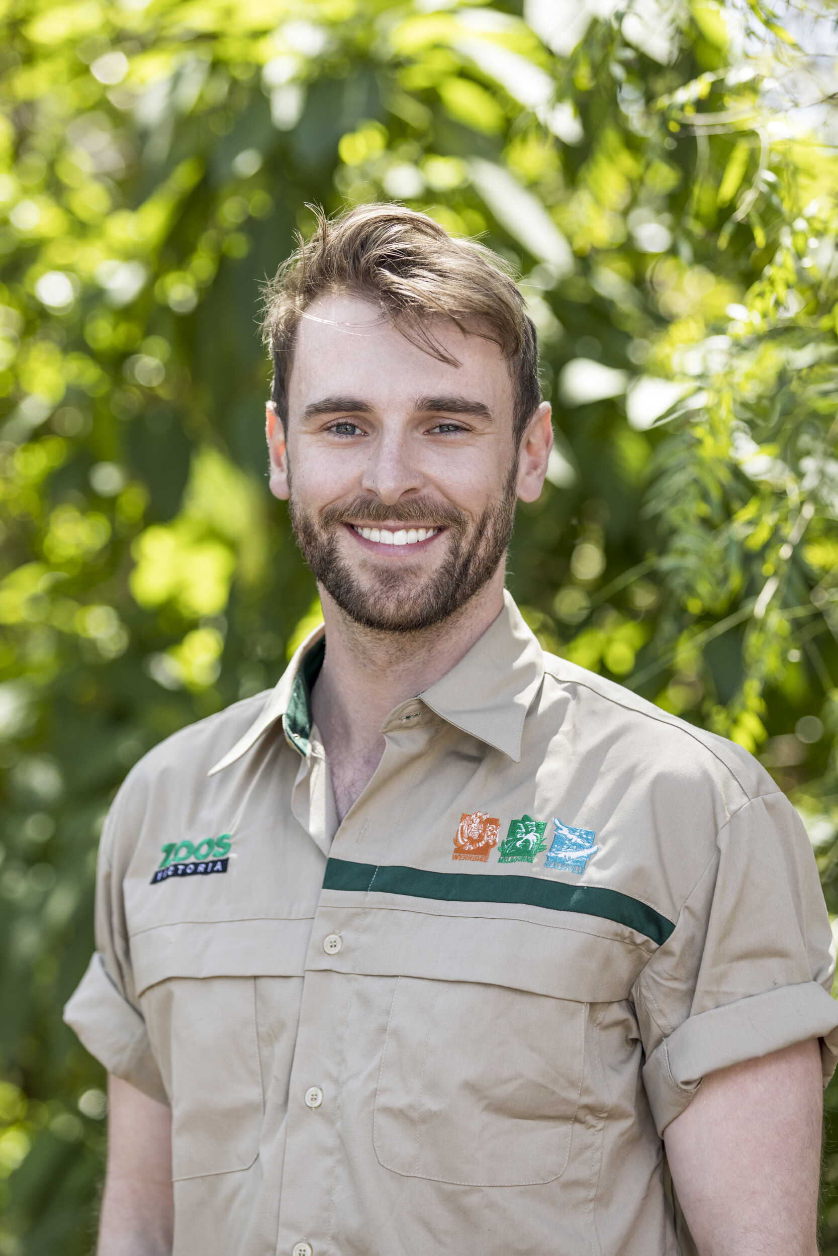Young man in zoo keeper uniform smiling at camera