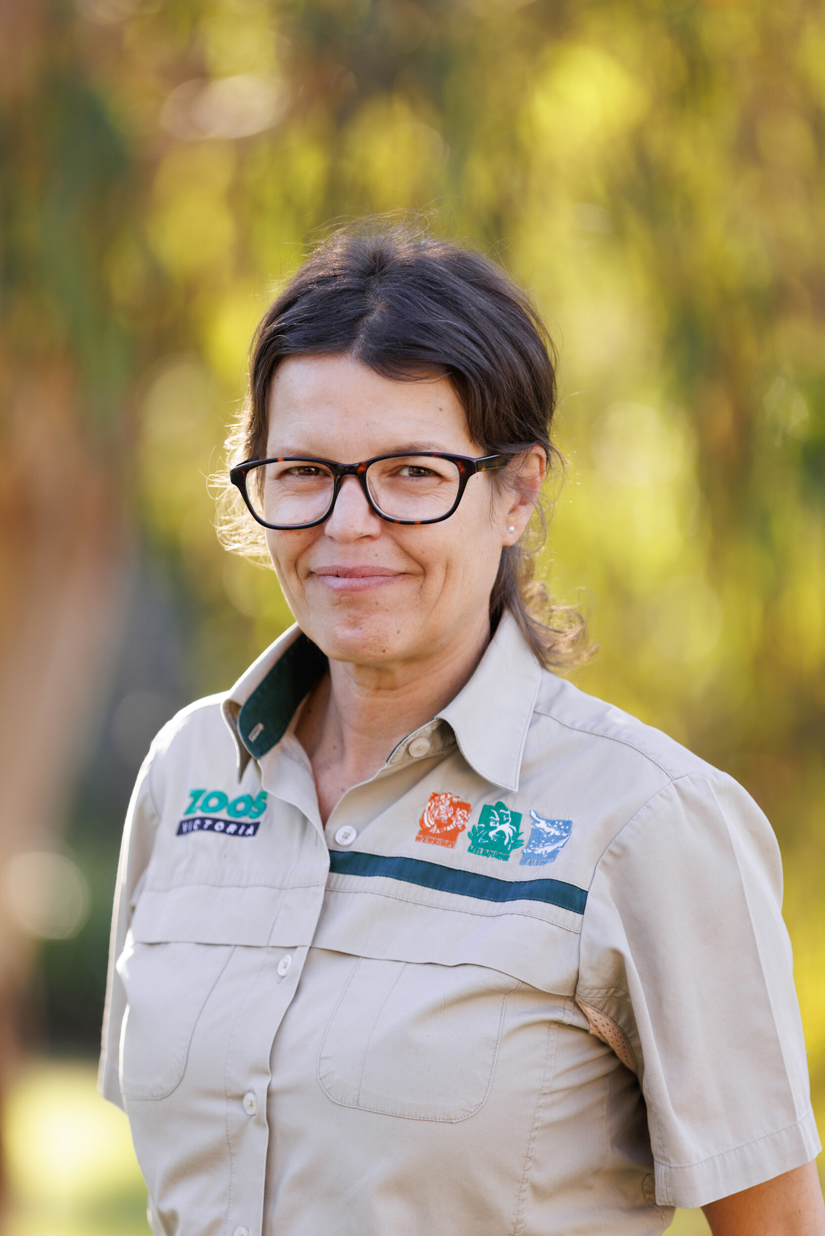 Smiling woman wearing glasses and a zoo keeper uniform