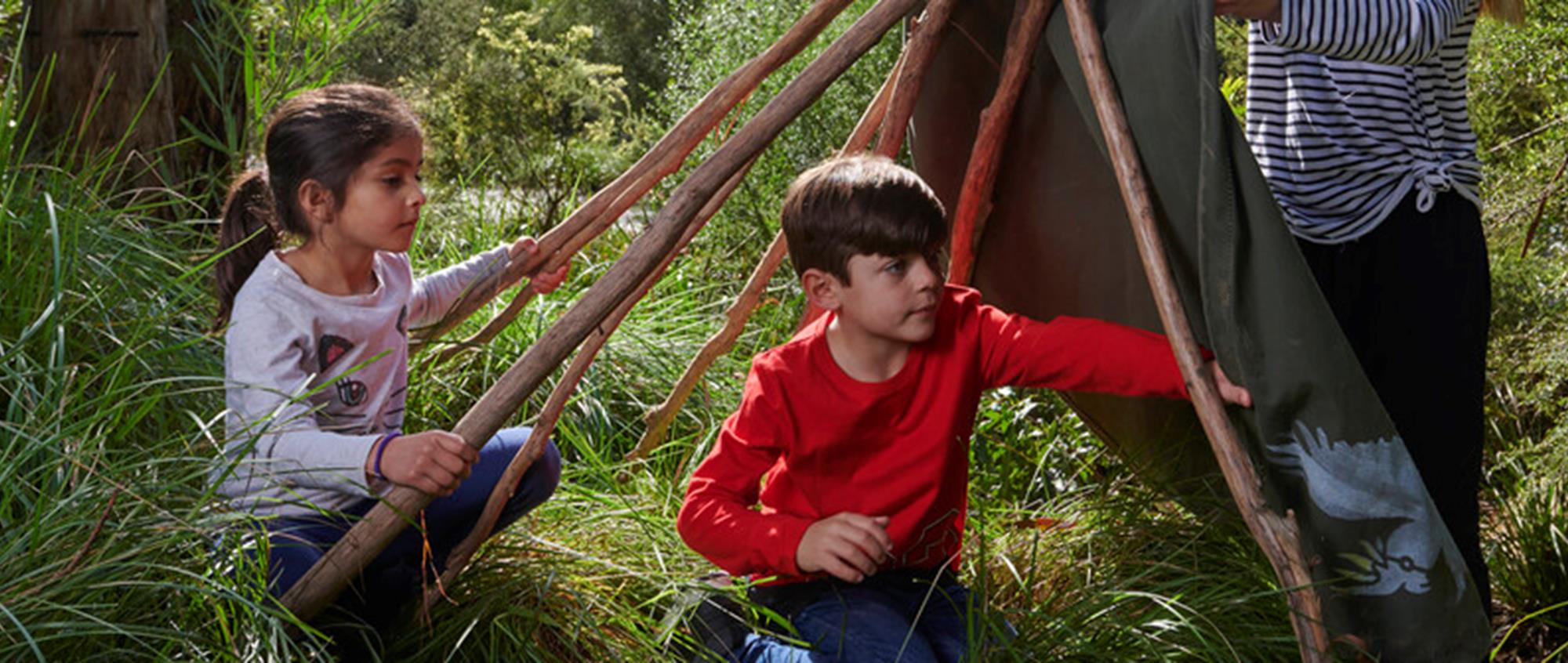 A young boy and girl build a gunyah shelter at Healesville Sanctuary