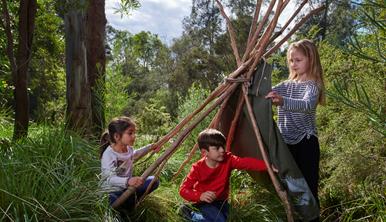 A young boy and girl build a gunyah shelter at Healesville Sanctuary