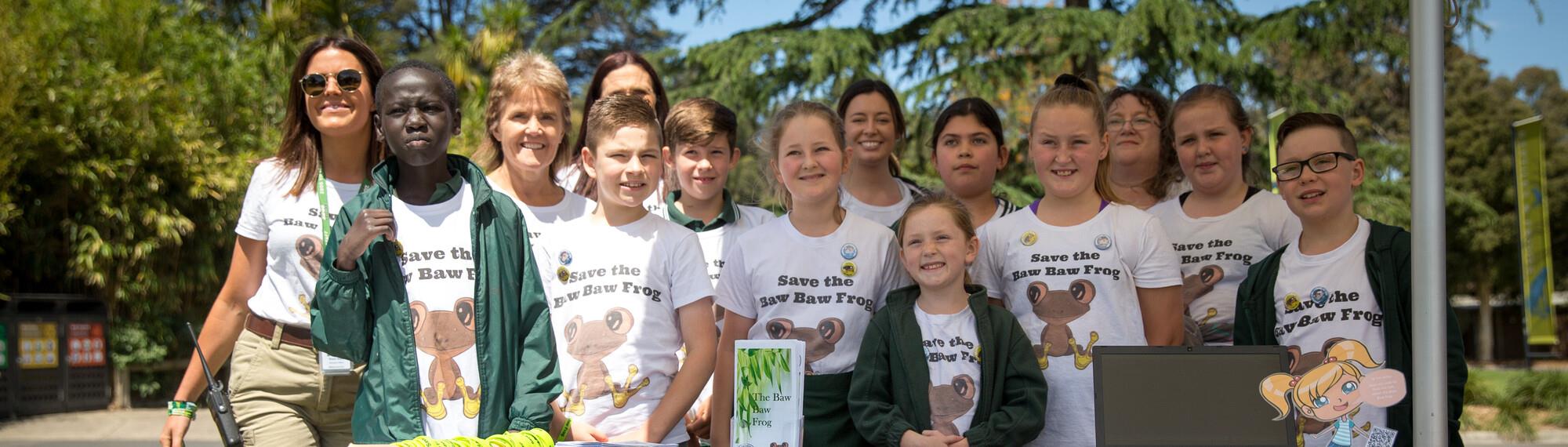 Ten students and four teachers, posing for their winning entry for the Fighting Extinction School Showcase, all wearing shirts with 'Save The Baw Baw Frog.'